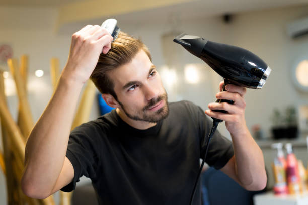 Female hairdresser combing and drying his own hair in hair salon stock photo