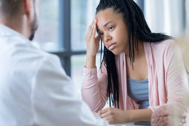 l'adolescente speranzosa ascolta il piano di trattamento dell'emicrania del medico - patient doctor male talking foto e immagini stock