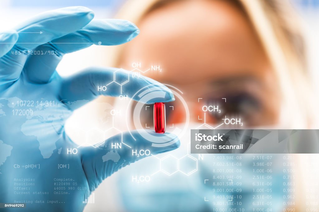 Young attractive female scientist holding a red transparent pill Young attractive female scientist holding a red transparent pill with futuristic scientific air interface with chemical formulas and research data in the foreground Medicine Stock Photo