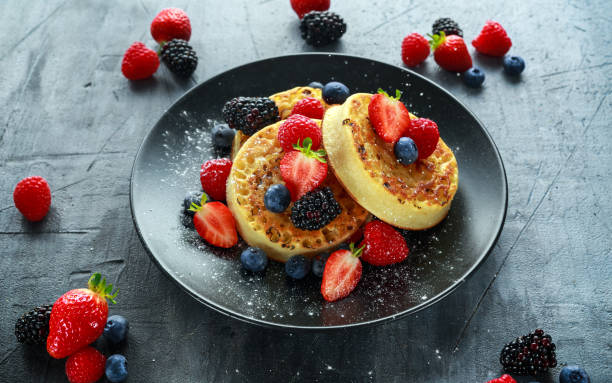 istock British Crumpets breakfast with blueberries, strawberries, blackberries, raspberries drizzled with icing sugar 849479834
