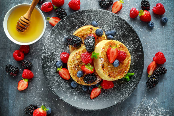 istock British Crumpets breakfast with blueberries, strawberries, blackberries, raspberries drizzled with icing sugar 849479900