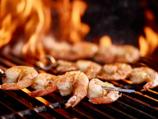 grilling shrimp on skewer on grill with flames