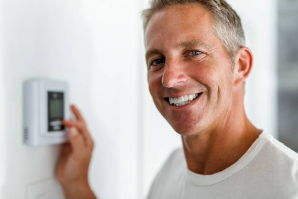 istock Smiling Man Adjusting Thermostat On Home Heating System 849493026