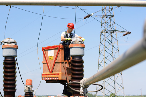 Construction worker fixing electricity equipment on a cherry picker