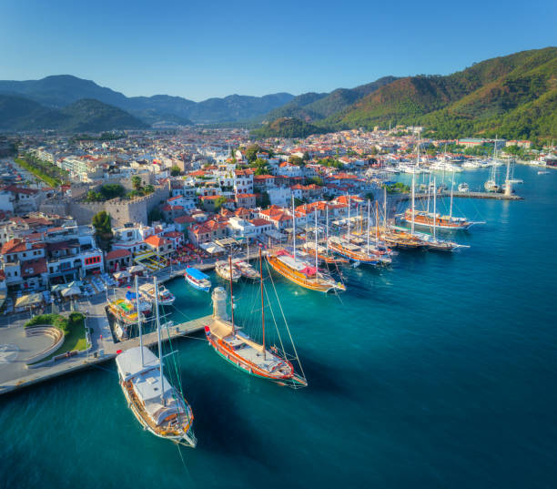 Aerial view of boats and beautiful architecture at sunset in Marmaris, Turkey. Colorful landscape with boats in marina bay, sea, city, mountains. Top view from drone of harbor with yacht and sailboat stock photo