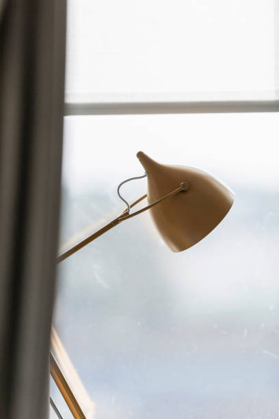 istock Vintage desk lamp in window frame behind curtain. 849516952