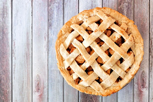 Rustic homemade apple pie with lattice pastry, above view on aged wood