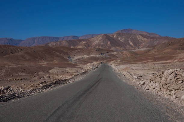 strada attraverso il deserto di atacama - arid climate asphalt barren blue foto e immagini stock