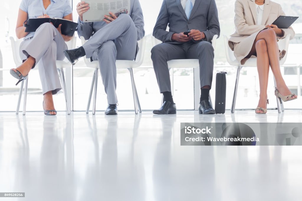 Group of well dressed business people waiting Group of well dressed business people waiting in waiting room Newspaper Stock Photo