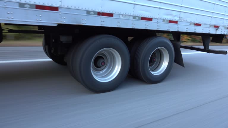 CLOSE UP: Freight semi truck passing by on highway, tires and wheels rolling