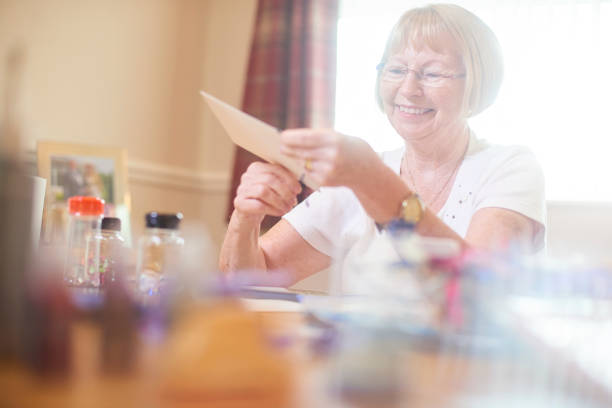 istock Senior woman smiling as she makes greetings cards 849551226