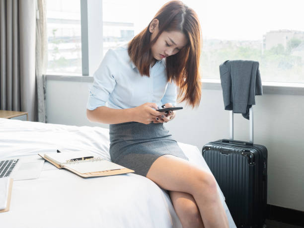 istock Woman sitting on bed typing cell phone 849575244