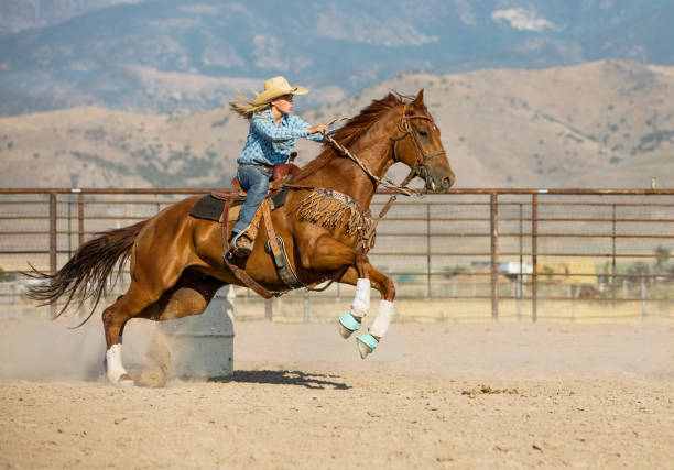 young cowgirl carrera de caballos entre barriles - cowgirl fotografías e imágenes de stock