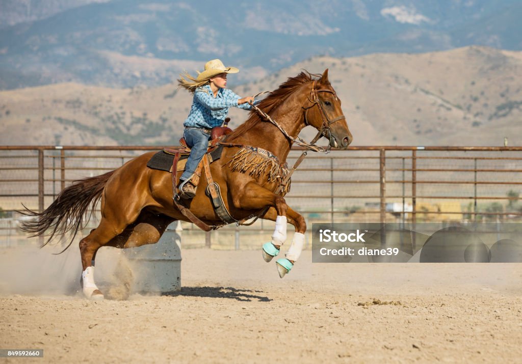 Young Cowgirl Barrel Racing A teenage cowgirl barrel racing with her beautiful horse. Rodeo Stock Photo