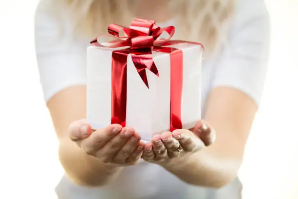 product photo of Christmas valentines gift present white colour red ribbon hands out of focus background girl holds blonde hair