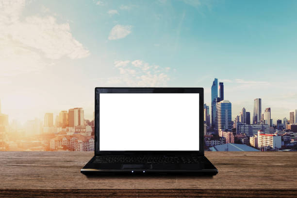 Laptop computer blank white screen on wood table with city view in sunrise. Clipping path computer screen