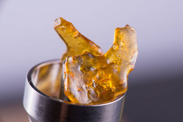 Piece of cannabis oil concentrate aka shatter on a titanium dab rig Macro detail of piece of cannabis oil concentrate aka shatter on a titanium dab rig dab dance photos stock pictures, royalty-free photos & images