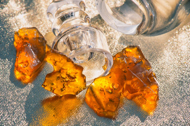 Pieces of cannabis oil concentrate aka shatter with glass rig stock photo
