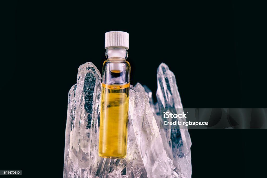 Detail of cannabis oil container and quartz crystal isolated on black Detail of cannabis oil container and quartz crystal isolated on black - medical marijuana concept Wax Stock Photo