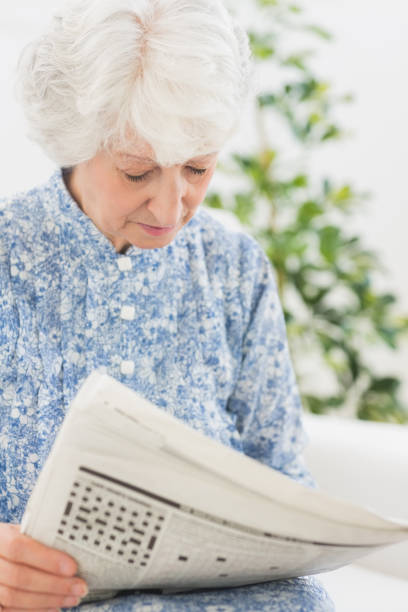 istock Elderly focused woman reading newspapers 849676234