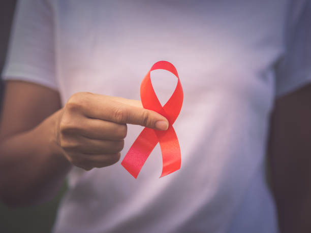 rote farbe band bewusst auf junge frau hand hintergrund: welt-aids-tag symbolisch konzept. - dezember stock-fotos und bilder