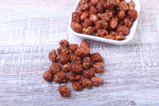 istock Sugared Hazelnuts in a white bowl on a wooden background. Hazelnuts in sugar glaze. Selective focus. 849686718