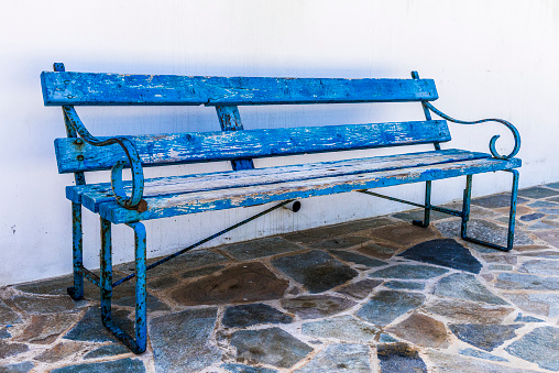 Shabby old bench by the wall of the Orthodox Church on coast of Cyprus.