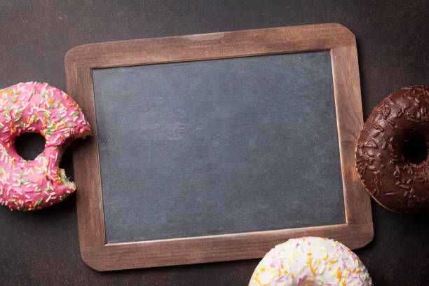 istock Chalkboard and colorful donuts on stone table 849691702