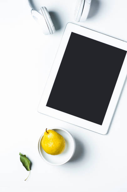 istock Yellow pear in a white Cup and mobile gadgets on a white background 849692624