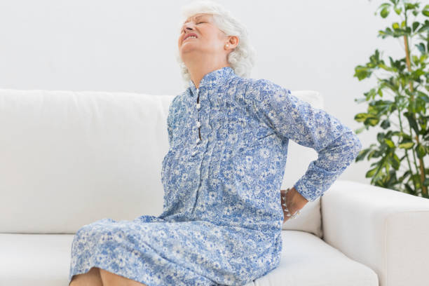 Elderly woman feeling back pain Elderly woman feeling back pain on the couch The Impact of Sleep on Back Pain: Muscle Relaxation Understanding the Connection in 60 year old  stock pictures, royalty-free photos & images