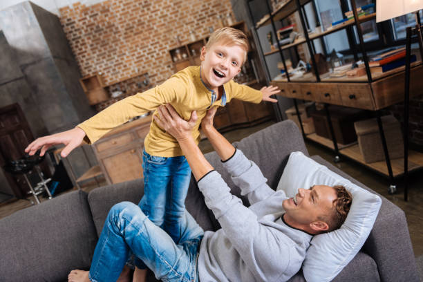 istock Joyful boy playing with his father on sofa 849707354