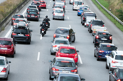 Hamburg, Germany - September 18. 2017: Traffic jam on the motorway in Hamburg, Germany. Two motorbike riders have to pass during a traffic jam improperly in the middle of the road.