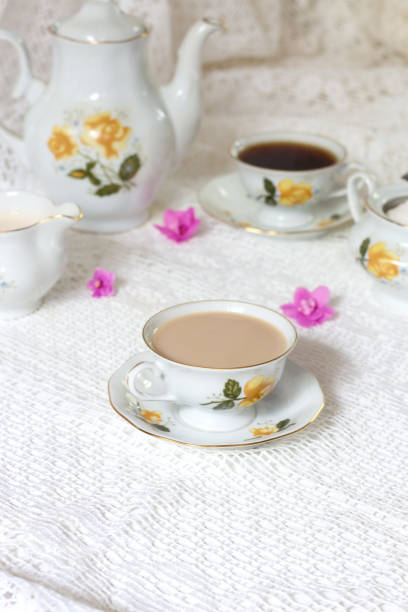 istock A tea cup decorated with flowers, two biscuits and a candle on a white wooden table. In the background a turquoise clock on a yellow wainscot. Vintage tea time 849722016