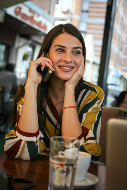 istock Young woman having coffee break and talking on smart phone in cafe. 849727146