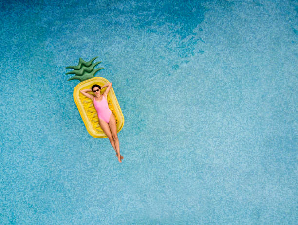 carefree woman on inflatable pineapple - bikini summer vacations looking down imagens e fotografias de stock