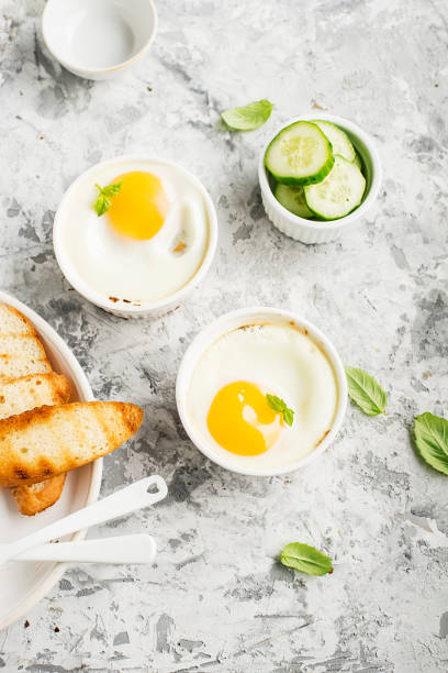 istock Breakfast for two. Eggs baked in the oven in ceramic portioned forms with toasted bread and slices of fresh cucumber. Top View. 849731522