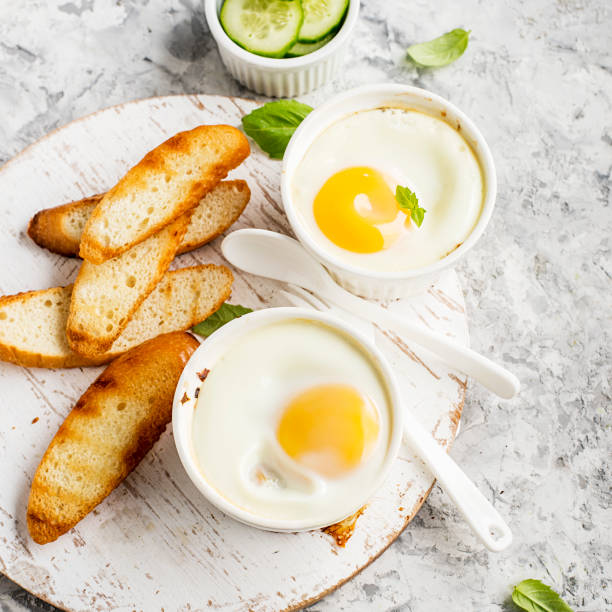 istock Breakfast for two. Eggs baked in the oven in ceramic portioned forms with toasted bread and slices of fresh cucumber. Top View. 849731540