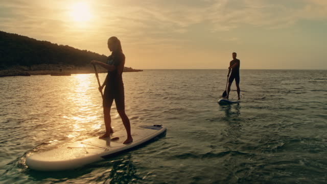 Couple paddling on their SUPs at sunset