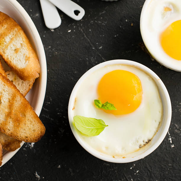 istock Breakfast for two. Eggs baked in the oven in ceramic portioned forms with toasted bread and slices of fresh cucumber. Top View. 849731706