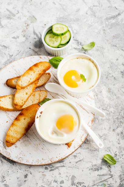 istock Breakfast for two. Eggs baked in the oven in ceramic portioned forms with toasted bread and slices of fresh cucumber. Top View. 849731914