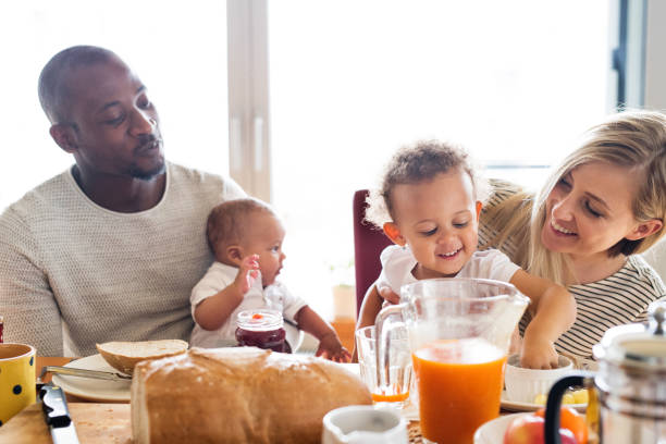 jovem família interracial com crianças tomando café da manhã. - little boys breakfast caucasian child - fotografias e filmes do acervo