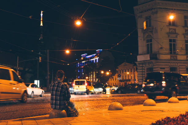 istock man sitting and looking at night city 849740784