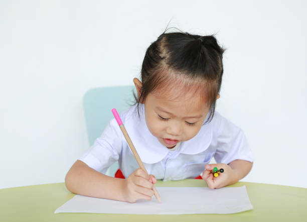 istock Asian child in school uniform with pencil writing on table isolated on white background. 849743770