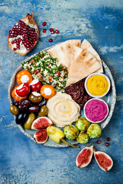 middle eastern meze platter with green falafel, pita, sun dried tomatoes, pumpkin and beet hummus, olives, stuffed peppers, tabbouleh, figs. mediterranean appetizer party idea - olive green olive stuffed food imagens e fotografias de stock