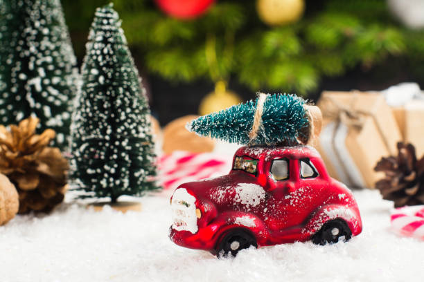 Miniature red car carrying fir tree on Christmas background stock photo