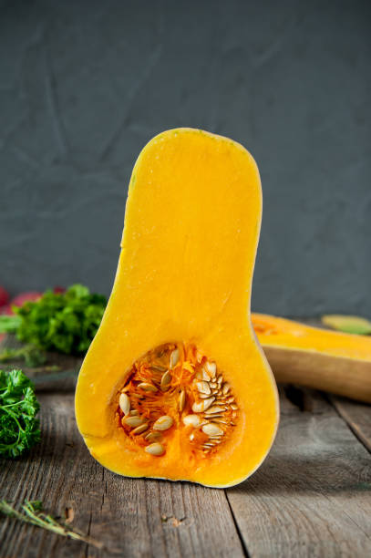 istock Part of ripe orange pumpkin with seeds standing on the rustic wooden table on the dark grey stone background. Vegetarian, vegan, healthy diet food. Autumn harvest. Selective focus. Space for text. 849800982