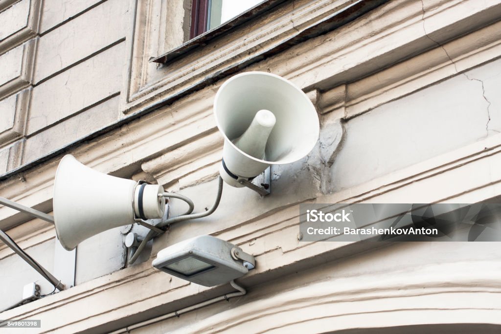 White megaphones on old building Warning citizens by loudspeakers on the wall. White megaphones on old building Amplifier Stock Photo