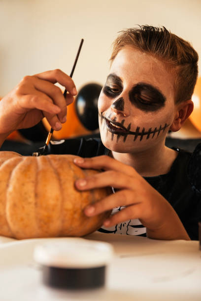 istock Happy boy decorating a pumpkin at home. 849805624