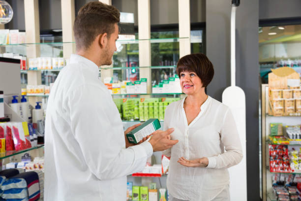 istock Man pharmacist helping customers in drug store 849819228