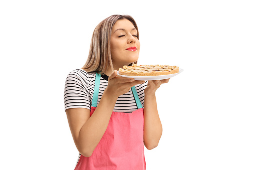 Young woman smelling a freshly baked pie isolated on white background